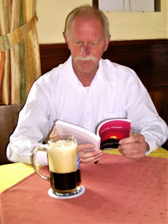 Foto  von Vinzenz Dorn mit Buch in der Hand und Bierkrug